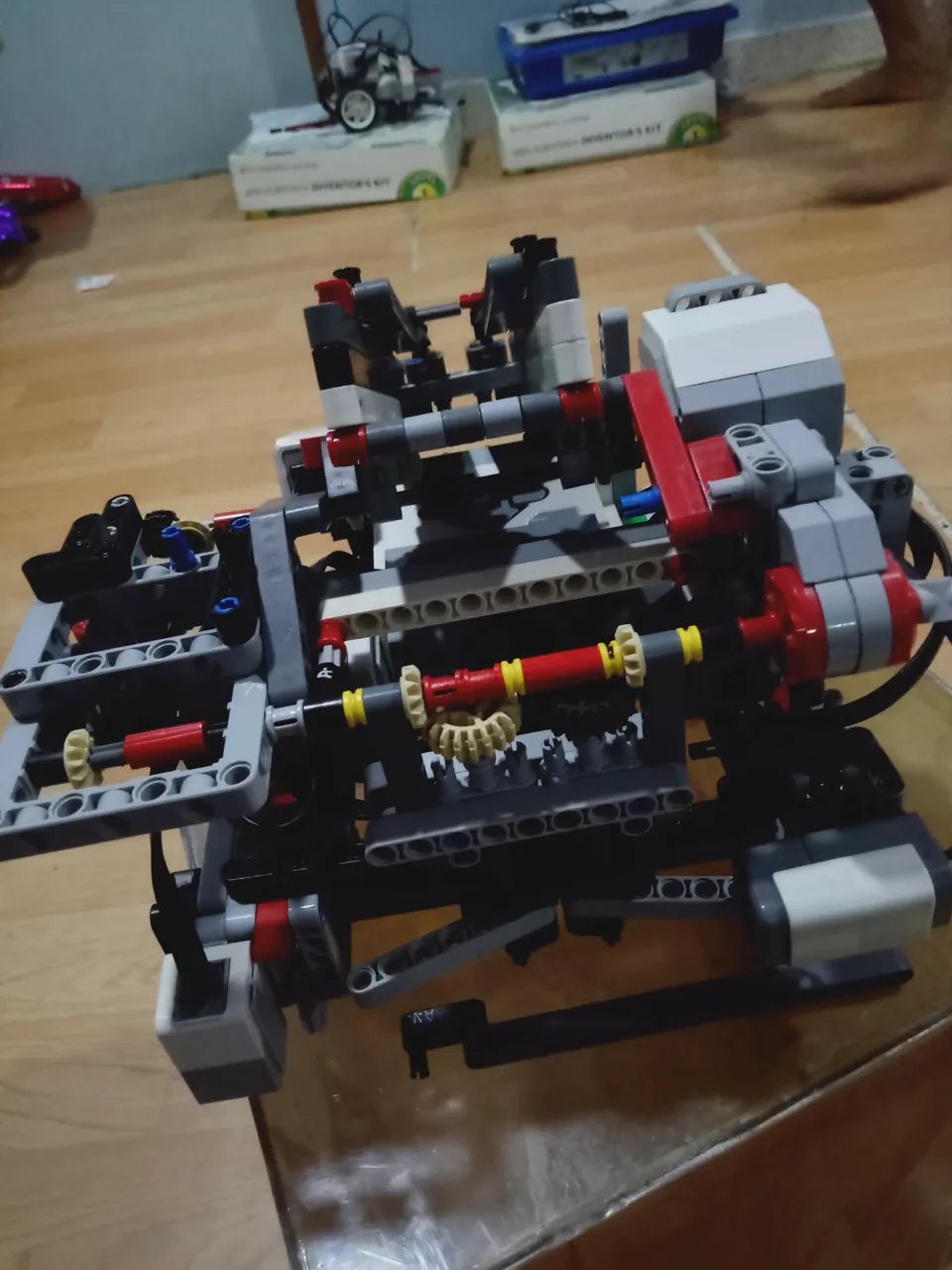 The robot from the side: LEGO motors, gears and axles, with Arduino kit boxes behind it.