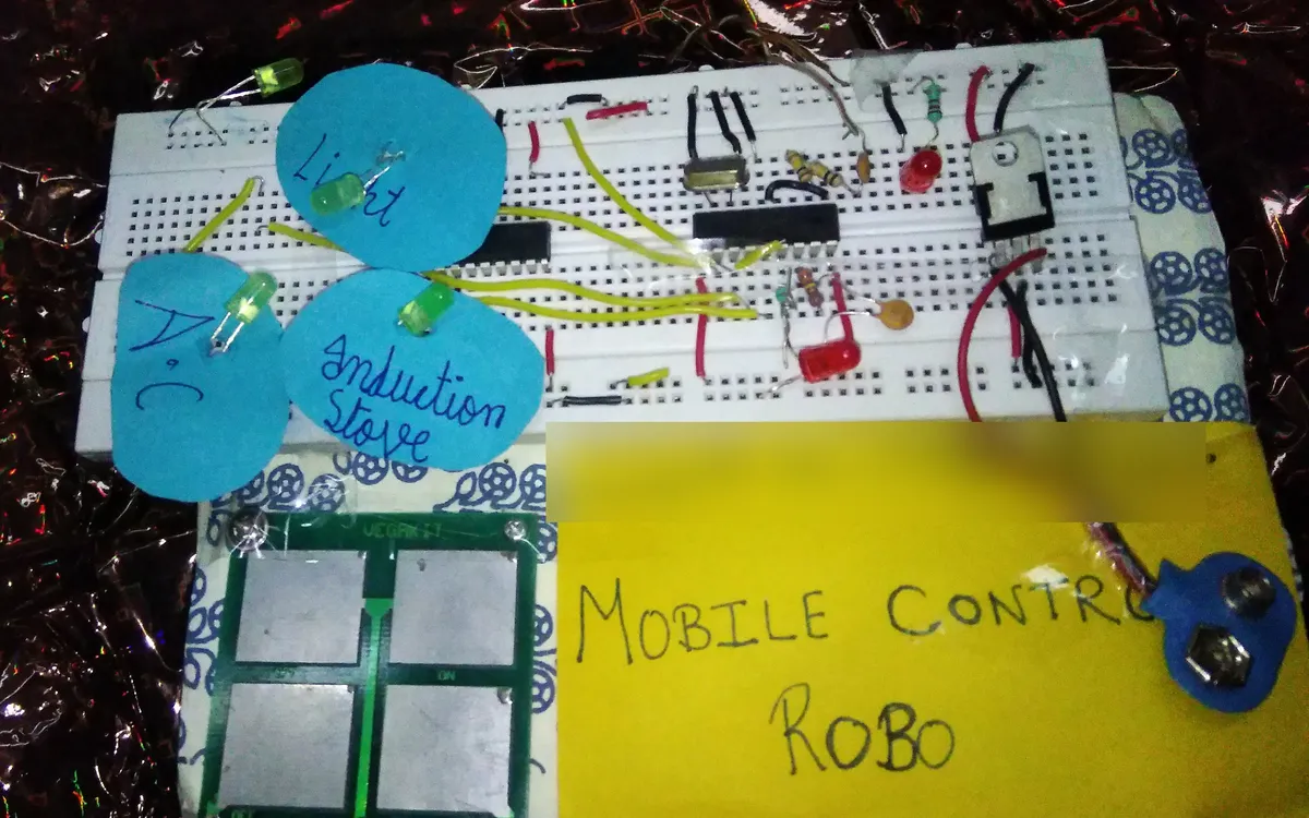My Mobile Control Robo on a breadboard: LEDs labelled light, AC and induction stove, a four pad touch plate, and its hand written sign.