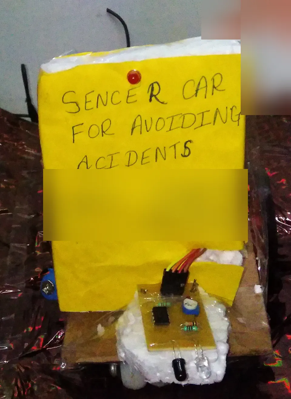 My sensor car for avoiding accidents, with its hand written yellow sign and a small sensor board at the front.