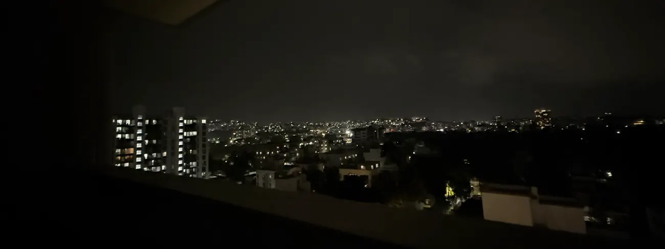 A city at night through the office window in July 2025, lit tower blocks on the left.